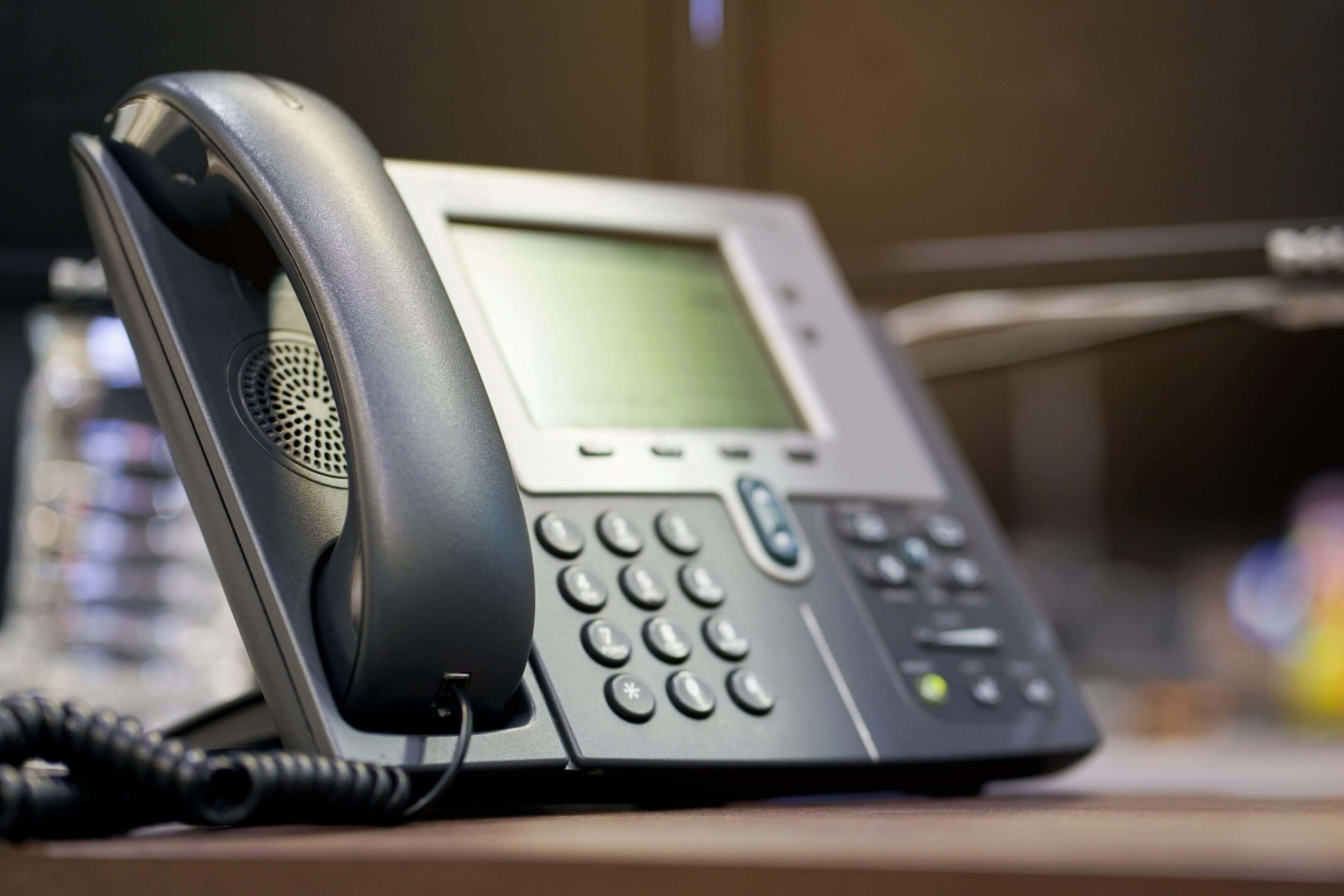 Close-up of a modern office desk phone with a digital display and keypad.