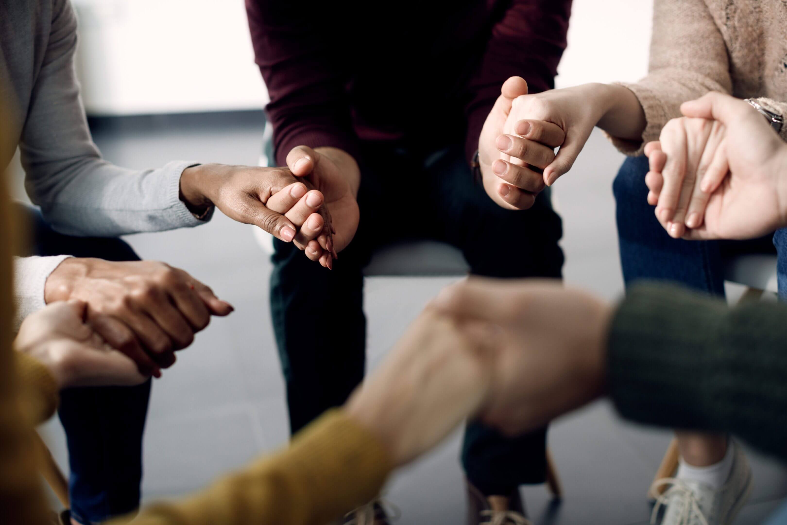 People holding hands in a supportive circle.